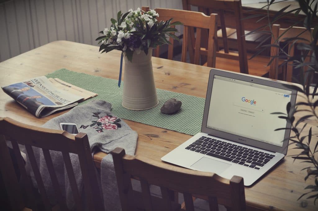 laptop on top of table beside vase of flowers