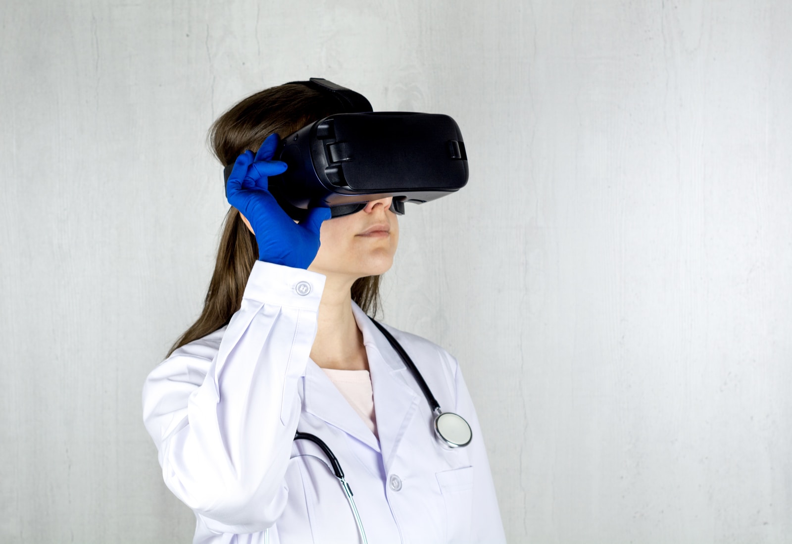 woman in white coat holding blue and black vr goggles